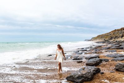 Woman standing on beach against sky