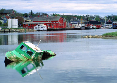 Buildings by river against sky in city