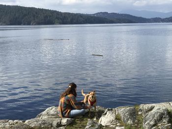 Women sitting on lake against mountains