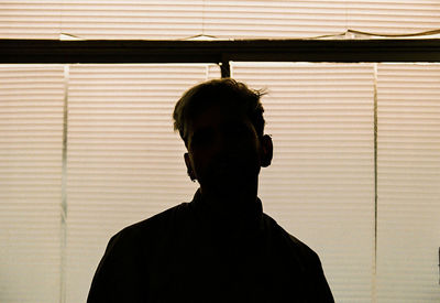 Portrait of silhouette man standing against window