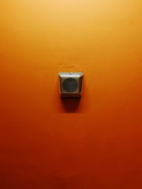 Close-up of electric lamp against orange wall