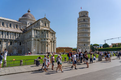 Crowd of tourists visit leaning tower of pisa in summer time