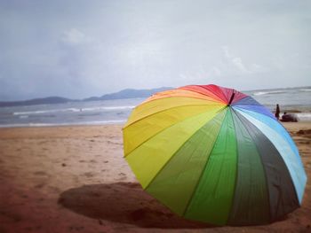 Close-up of multi colored umbrella on beach against sky
