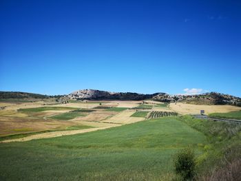 Scenic view of farm against clear blue sky
