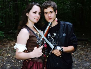 Portrait of beautiful young woman holding camera while standing outdoors