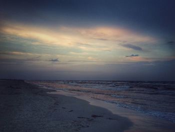 Scenic view of beach against sky at sunset