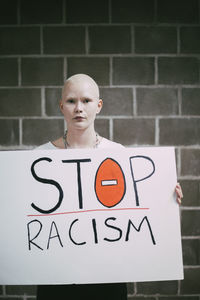 Young female protestor with stop racism sign against wall