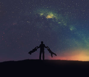 Silhouette man standing on field against sky at night