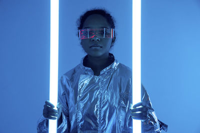 Woman holding illuminated neon lights against blue background
