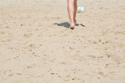Low section of woman walking on sand at beach