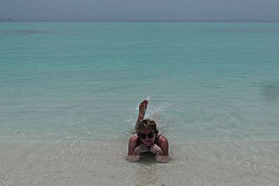 Shirtless man in sea against sky