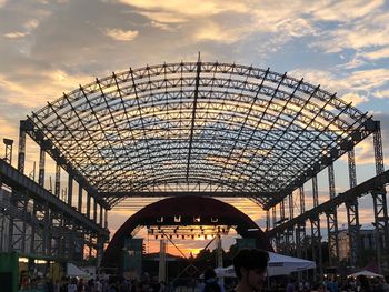 People in modern building against sky during sunset