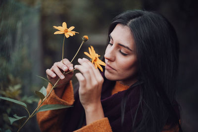 Young woman smelling a yellow flower in the field