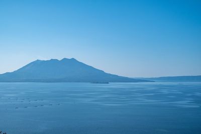 Scenic view of lake and mountains against clear blue sky