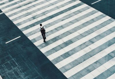 High angle view of man walking on zebra crossing in city