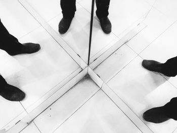 Low section of men standing on tiled floor