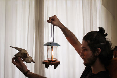 Side view of man holding lamp