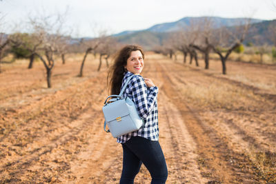 Portrait of young woman standing on field