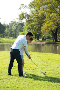 Full length of couple playing golf on field