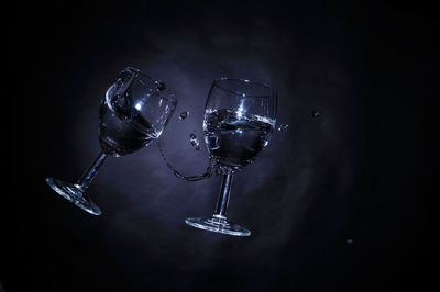 Close-up of wineglasses falling against black background