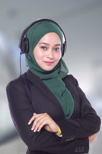 Portrait of confident businesswoman with headphones wearing hijab at call center