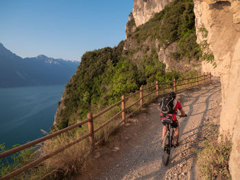 Rear view of man riding bicycle on mountain road