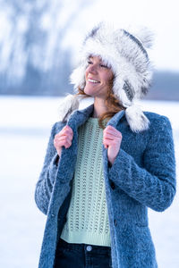 Portrait of smiling young woman wearing warm clothing standing outdoors