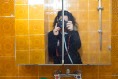 Reflection of woman photographing in mirror