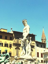 Statue in front of building against clear blue sky