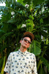 A young guy wearing summer clothing. palm tree as background.