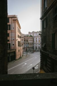 Road by buildings against sky in city