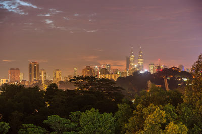 Illuminated buildings in city against sky at night