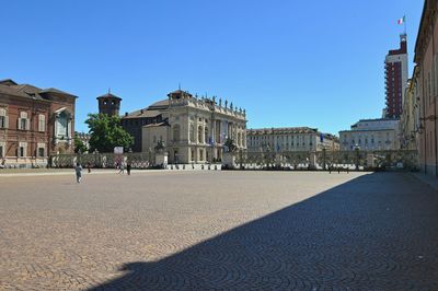 Buildings in city against clear blue sky