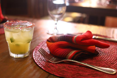 Table setting with tablecloth margarita and silverware indoors backlit