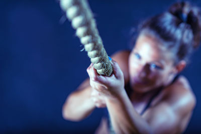 High angle view of female athlete climbing on rope in gym