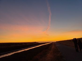 Road amidst silhouette landscape against sky during sunset