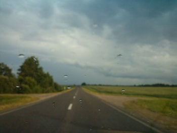 View of country road against cloudy sky