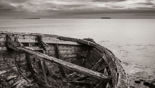 Abandoned boat on beach against sky