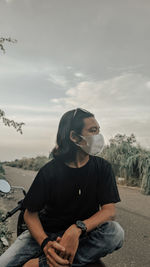 Young woman looking away against sky