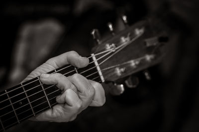 Close-up of man playing guitar against black background