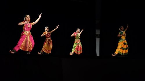 Group of people dancing against black background