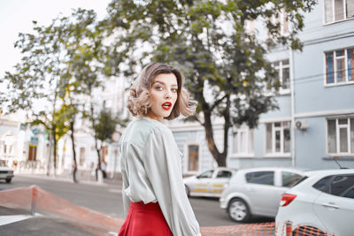 Woman standing by car in city