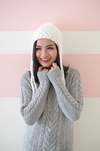 Portrait of a smiling young woman standing against wall