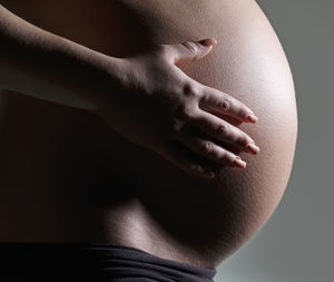 Close-up of woman touching hair over black background