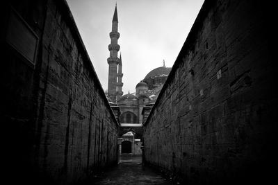 Narrow alley amidst wall against mosque in city