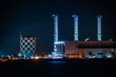 Illuminated factory against sky at night