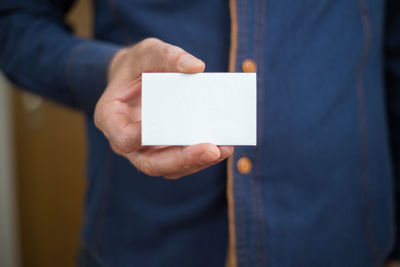 Midsection of man holding paper