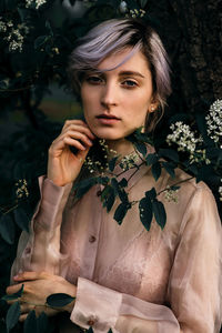 Portrait of young woman standing by plants at park