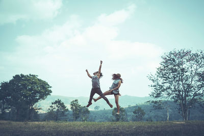 People jumping on field against sky