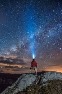 Man standing on rock against sky at night